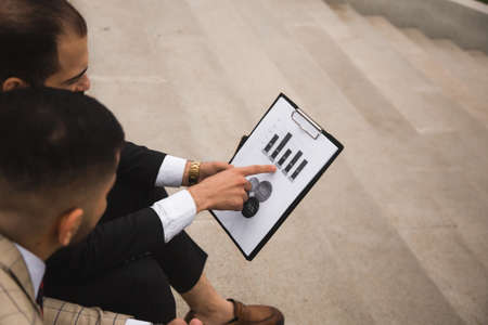 A group of business people meet outdoors. Male employees in suits communicate outdoors. Business...