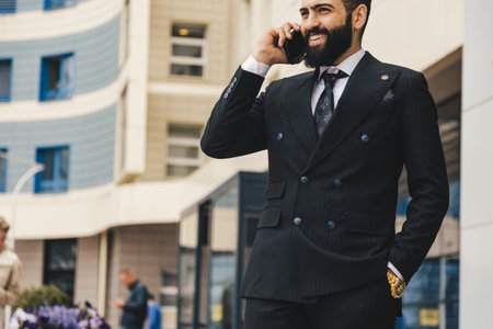 Portrait of a business man outdoors using the phone against the backdrop of a glass building downtown.の写真素材