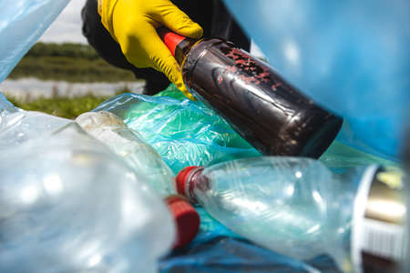 Close-up of a hand throwing garbage into a plastic bag. View from inside the bag. The concept of...