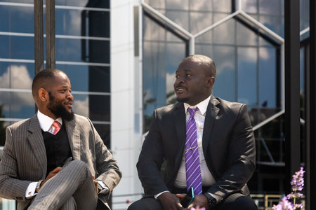 Two dark-skinned businessmen in suits communicate. Friends and business partners are sitting on a...