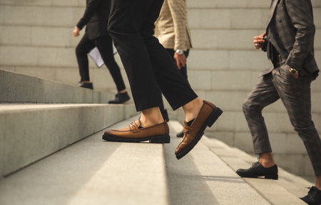Business people climb the stairs of the city stairs. Close-up of the impersonal legs rising up. Career growth and advancement. Increasing and improving skills. Salary increaseの写真素材