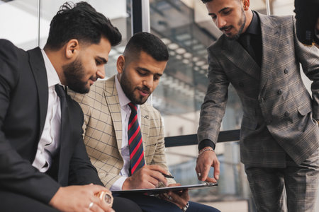 Business people outdoor meeting. A group of business people meet outdoors. Male employees in suits communicate outdoors. Business partners discuss and argue. Relationships and promotion.の写真素材