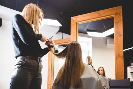 Master woman hairdresser cuts the ends of the girls hair after washing and before styling in a beauty salon.の写真素材