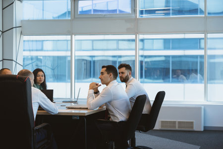 Group of young business people working and communicating while sitting at the office desk together with colleagues sitting. business meetingの写真素材