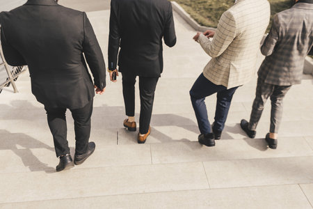 A group of business men in suits descends the city stairs. outdoors. Working break. Collaboration...