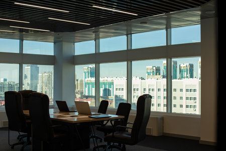 The interior of an empty modern office with a table and chairs and a meeting room with panoramic windows against the backdrop of the buildings of a big cityの写真素材