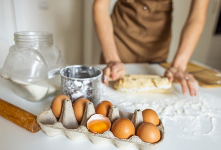 A woman in a special apron cooks at home. Rolling out and preparing dough for baking.の写真素材