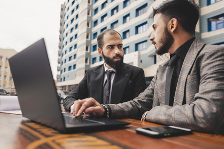 business people meets outdoors. Two men are using a laptop. Working break. Team and business support. Collaboration and partnershipの写真素材