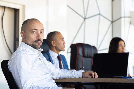 Business portrait of a male professional manager at a meeting with colleagues in a conference roomの写真素材