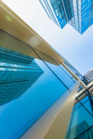 The blue sky is reflected in the windows of a modern office building. Architecture and exterior of...