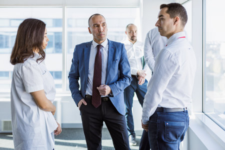 Business portrait of a male professional manager communicating at a meeting with colleagues in a meeting room by the window in the officeの写真素材