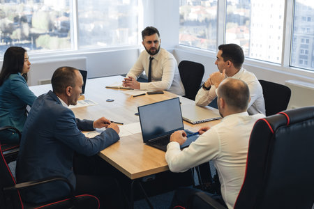 Group of young business people working and communicating while sitting at the office desk together with colleagues sitting. business meetingの写真素材