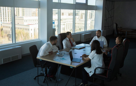 Silhouettes of people sitting at the table. Team of young business people working and communicating...