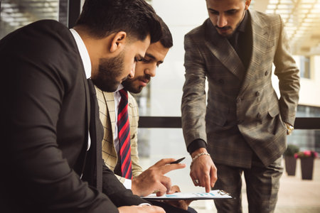 An international successful business team of male entrepreneurs in suits met to discuss development ideas. Efficient work and corporate spiritの写真素材