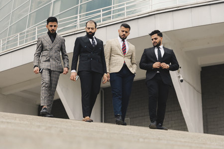 Business people outdoor meeting. A company of male businessmen in suits descend down the street stairs. Working break. Teamwork and brainstorming. Successful teamwork.の写真素材