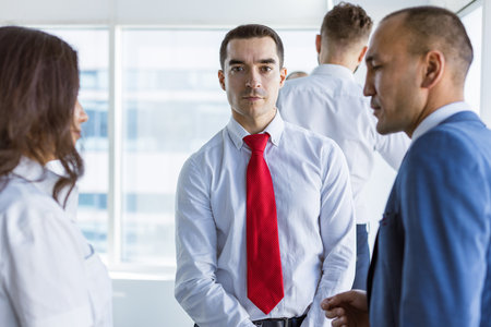A team of young businessmen working and communicating together in an office. Corporate businessteam and manager in a meeting.の写真素材