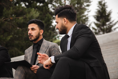 A group of business people meet outdoors. Male employees in suits communicate outdoors. Business partners discuss and argue. Relationships and promotion. Teamwork and friendshipの写真素材