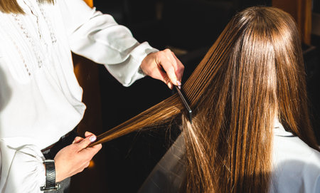Close-up hairdresser combs the girls hair by styling in a beauty salon.の写真素材