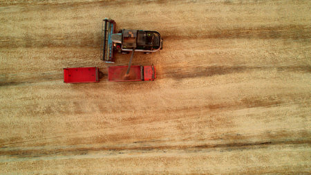 Aerial shot from above harvesters gathering crops from agricultural fields. Global food crisis and grain supply chainsの写真素材