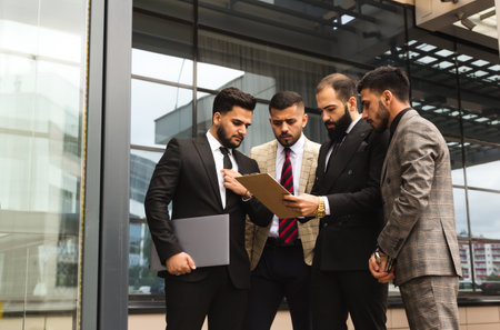 An international team of successful young business men in suits at a meeting are discussing the implementation of business plans together.の写真素材