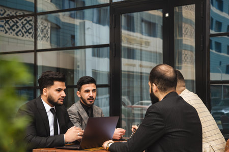 Corporate meeting of business partners outside the office. Male employees sit at the table and discuss the goals, ideas and plans of the company.の写真素材