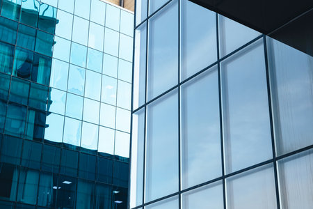 The blue sky is reflected in the windows of a modern office building. Architecture and exterior of contemporary housesの写真素材