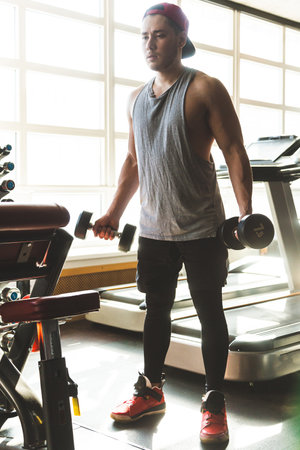 Silhouette picture of a man performing exercises with dumbbells in the gym. Strength trainingの写真素材