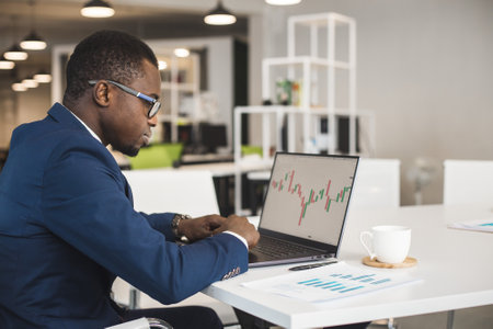 African American men in a business suit are working on a laptop studying stock market charts and technical analysis.の写真素材