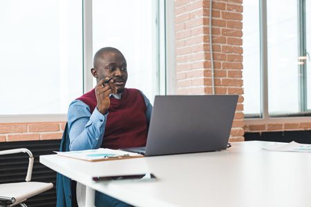 Portrait of an African American in the office. Black man in a business suit working on a laptopの写真素材