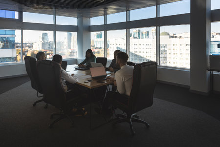 Silhouettes of people sitting at the table. Team of young business people working and communicating together in a modern office. Corporate team and manager in a meeting.の写真素材