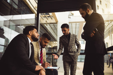Business partners jointly discuss the difficulties and the implementation of ideas. Young successful men in suits at a team meeting outside the officeの写真素材