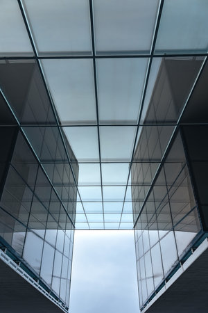 The blue sky is reflected in the windows of a modern office building. Architecture and exterior of contemporary housesの写真素材