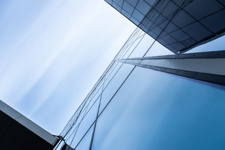 The blue sky is reflected in the windows of a modern office building. Architecture and exterior of contemporary housesの写真素材