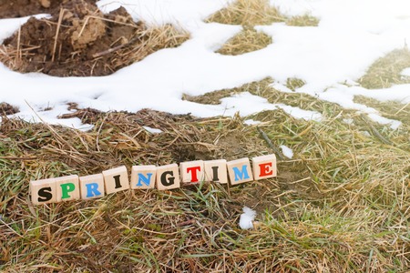 A colorful inscription spring made up of wooden cubes stands on a plowed field in spring. The beginning of the season of field work. Agro-industrial farm business. Snow melts on the groundの写真素材