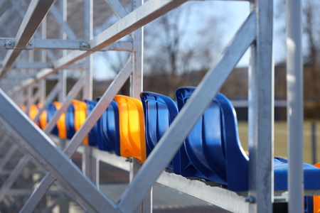 New stands on the football field of metal light construction with plastic seats in blue and yellow....