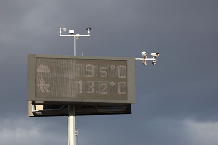 Electronic information board measuring temperature against the backdrop of thunderclouds. Security cameras and weather sensors. Infrastructure assistance to drivers on the highway. Warning of weather.の写真素材