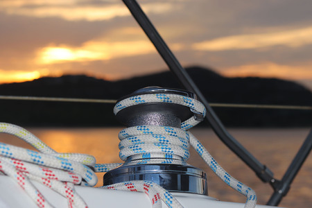 Skeleton winch on board a sailing cruise yacht. The view from the cockpit on the sunset background....