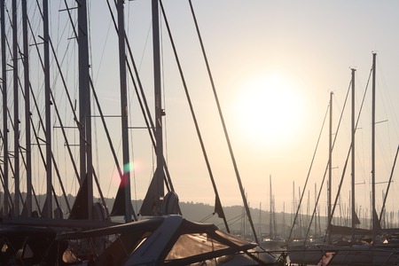 Masts of sailing yachts against the blue sky illuminated by the bright sun. Technologies of sailing...