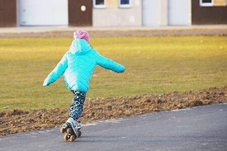 The girl rides on rollers on a new asphalt track in the spring season. Youth activity and healthy lifestyle. Sports training and competition. Use of sports equipment. The pursuit of victoryの写真素材