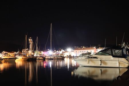Night parking of yachts in the Croatian ACI marina of the town of Jazira. Burning lights of the evening Mediterranean port with sailing yachts and fishing boats. Twilight on the Adriatic Riviera. Calm.の写真素材