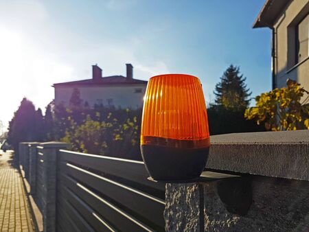 Orange room alarm light located on a brick fence post. Intercom apartment building at the entrance...