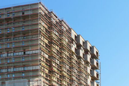 Construction of a high multi-storey building. Skyscraper furnished with metal scaffolding. Dangerous...