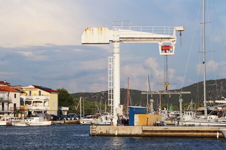Crane lift for raising boats in the marina ACI Jazera in Croatia. Dalmatian ragion of Adriatic sea at Mediterranean area. The ships moored in the port of a quiet fishing town in a sunny,clear day.の写真素材