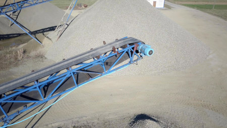 Elements of equipment for the extraction and sorting of rubble. Production of construction materials. Metal construction for working with stone and rocks. Slag of gravel under the conveyor beltの写真素材