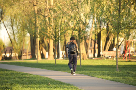 A young girl walks alone along a park alley. A walk in the fresh air among summer greenery.の写真素材