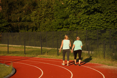 Two women running on a track in a sunny summer day.