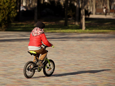 A boy rides a bicycle in the park on a sunny spring day. Children's activity for the harmonious development of the teenage generation. Game in the fresh air. Equilibrium on a two-wheeled transport.の写真素材