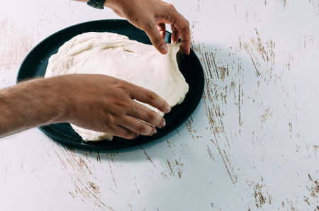 Chef making homemade pizza by rolling out pizza dough