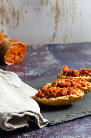 Three sobrasada montaditos on a slate plate with a linen cloth and a sobrasadaの写真素材