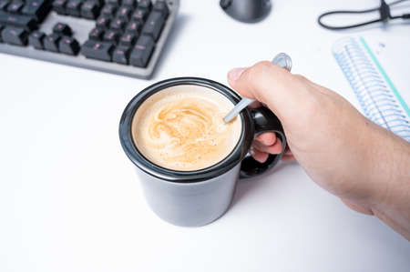 Putting coffee with milk at work time in home officeの写真素材